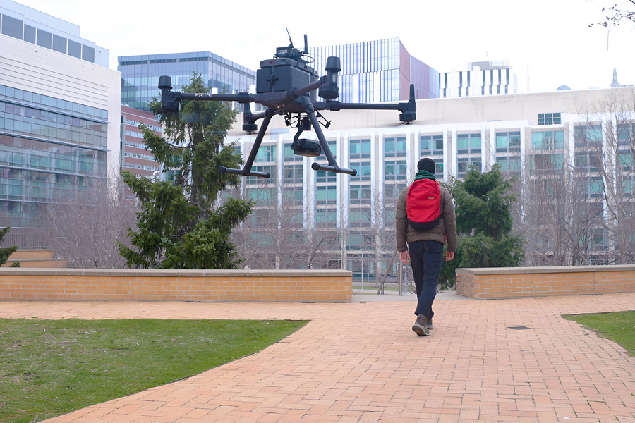 MIT researcher walks near drone, which is using brain-inspired liquid neural networks that excel in unseen environments.