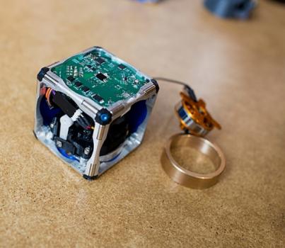 A prototype of a new modular robot, with its innards exposed and its flywheel — which gives it the ability to move independently — pulled out.