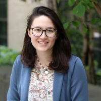 A picture of Victoria Preston sitting in front of MIT buildings and amongst greenery.