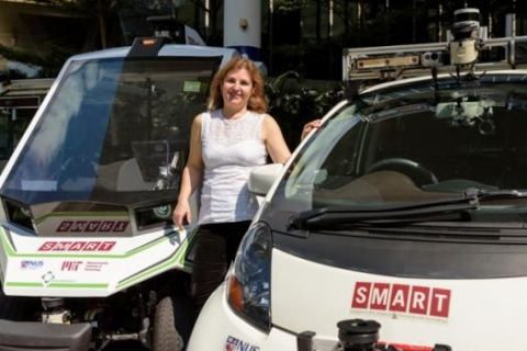 Professor Daniela Rus stands with autonomous SMART vehicles on the MIT campus. 